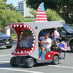 a man driving a golf cart with a shark's mouth on the front and side