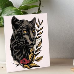 a black cat with yellow eyes and leaves on it's head art board print