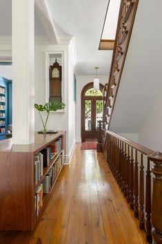 a long hallway with bookshelves and wooden flooring next to a stair case