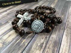 This brown wooden cord rosary is simple yet perfect! It fits nicely in the pocket and is lightweight, great for anytime. This particular cord rosary is made with 10mm dark wood beads and nylon cord. The beads are strung on and then I make a fancy not on either side of the glory be bead. It is adorned with the Holy shroud centerpiece and the Holy Trinity crucifix. Materials used: ~10mm Wood beads ~Nylon cord ~Shroud centerpiece ~Trinity crucifix *Made in my pet and smoke free home. CautionNot for Brown Cross-shaped Rosary With Wooden Beads, Brown Wooden Beaded Cross Rosary, Brown Cross Rosary In Spiritual Style, Brown Cross-shaped Spiritual Rosary, Brown Spiritual Rosary With Cross, Brown Cross Shaped Spiritual Rosary, Brown Rosary With 8mm Beads And Cross Shape, Brown Rosary With 8mm Beads, Catholic Christmas Gifts