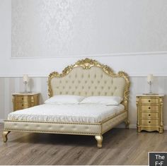 a white and gold bedroom with a bed, nightstands and two lamps on the floor