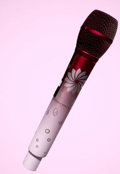 a red and white microphone with flowers on the top is in front of a pink background