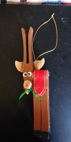 a wooden reindeer ornament hanging on a black surface with a string attached to it