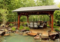 an outdoor gazebo with chairs and tables next to a pond