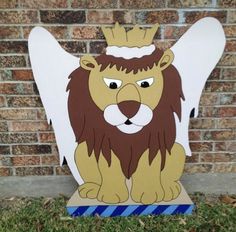 a cardboard cutout of a lion with a crown on its head, sitting in front of a brick wall