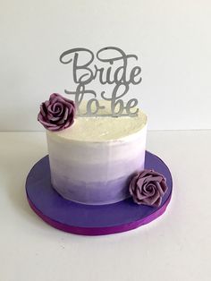 a purple and white cake sitting on top of a purple platter with two flowers