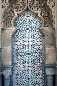 an intricately designed door with blue and white tiles on the side of a building