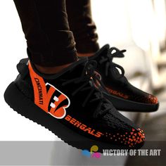 the feet of a person wearing black and orange shoes with an orange logo on them