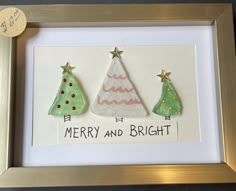 three small christmas trees are displayed in a gold frame with the words merry and bright written on it