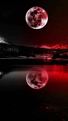 the full moon is reflected in water with mountains in the background and red light reflecting on it's surface