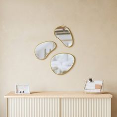 three mirrors are hanging on the wall above a white dresser and sideboard with drawers