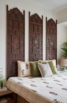 a bed with pillows and decorative wooden headboard