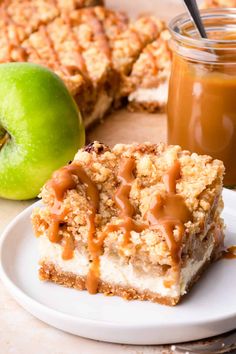 two pieces of dessert on a plate with an apple and caramel sauce in the background