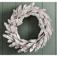 a silver wreath hanging on the side of a green wall