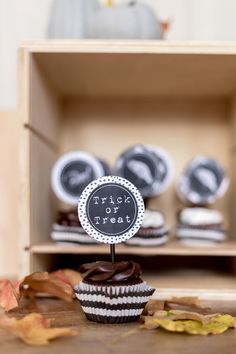 cupcakes with frosting sitting on top of a wooden table in front of an open box