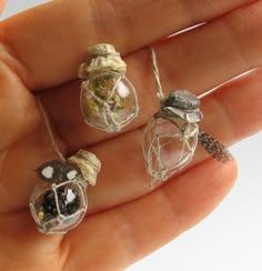 a person is holding three small glass beads in their hand, one with flowers on it and the other with leaves