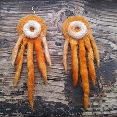 two orange and white stuffed animals hanging from earwires on wooden planked surface