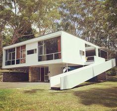 a white house sitting on top of a lush green field next to trees and grass