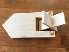 a wooden model of a house sitting on top of a wooden table next to a knife