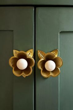 an egg is sitting in the center of a flower shaped door handle on a green door