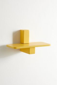 a yellow shelf on the wall next to a white wall