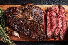 the steak is sliced and ready to be served on the grill, with herbs around it