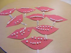 some pink paper plates with white beads on them sitting on top of a wooden table