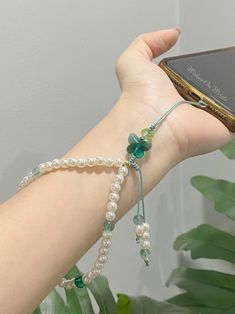 a person holding up a cell phone in their hand with pearls and beads on it