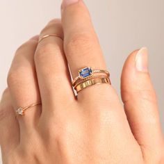 a woman's hand with three different rings on her left and the other one has a blue stone in it