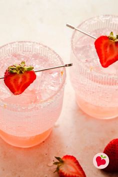 three glasses filled with ice and strawberries on top of a white counter next to silver spoons