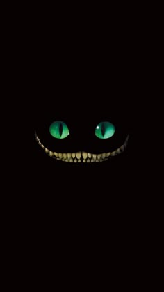 an evil looking face with glowing green eyes in the dark, showing teeth and fangs