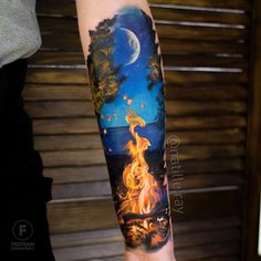 a person with a tattoo on their arm that has a fire in the forest and moon above it