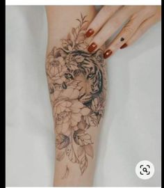 a woman's arm with flowers on it and a tiger in the middle of her arm