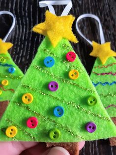 a hand holding a piece of felt with buttons on it and a christmas tree decoration