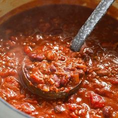 a ladle full of chili and beans in a pot