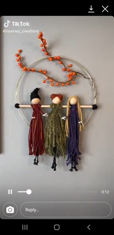 three dolls are hanging on the wall with orange beads and tassels around them