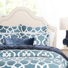 a bed with blue and white comforters in a bedroom next to a lamp on a nightstand