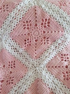 a pink and white crocheted blanket on top of a bed