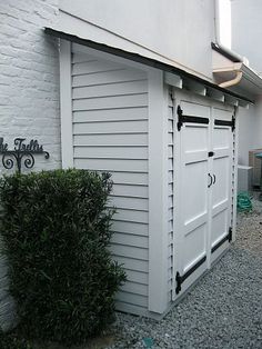 a white building with a black door and some bushes