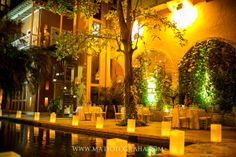 an outdoor dining area at night with lit candles on the ground and tables set up outside