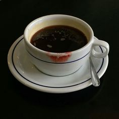 a white cup filled with liquid sitting on top of a saucer next to a spoon