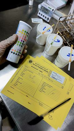 a person is holding a cup over a table with several cups and a calculator on it