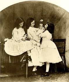 three women sitting on a bench with one woman holding a doll and the other standing up