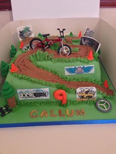 a cake that is shaped to look like a race track with cars and motorcycles on it