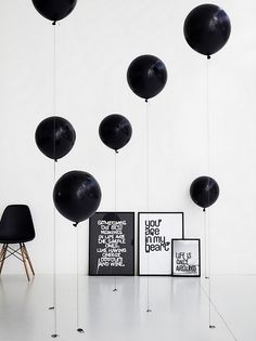 black balloons are floating in the air above a white room with chairs and framed pictures