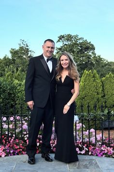 a man in a tuxedo and a woman in a black dress pose for a photo