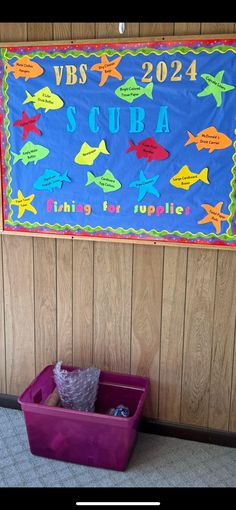 a bulletin board with fish on it in front of a wooden wall and carpeted floor