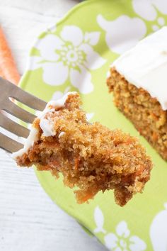 a piece of carrot cake with white frosting on a green and white flowered plate