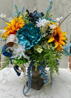 a vase filled with blue and yellow flowers on top of a white marble countertop