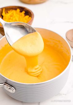 a ladle scooping cheese into a pot filled with soup